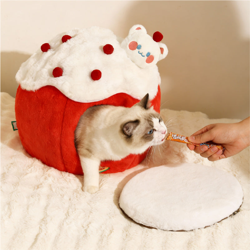 Snowball & Strawberry Cat Cave Bed — Soft & Cozy with a cat peeking out and a person offering a treat.