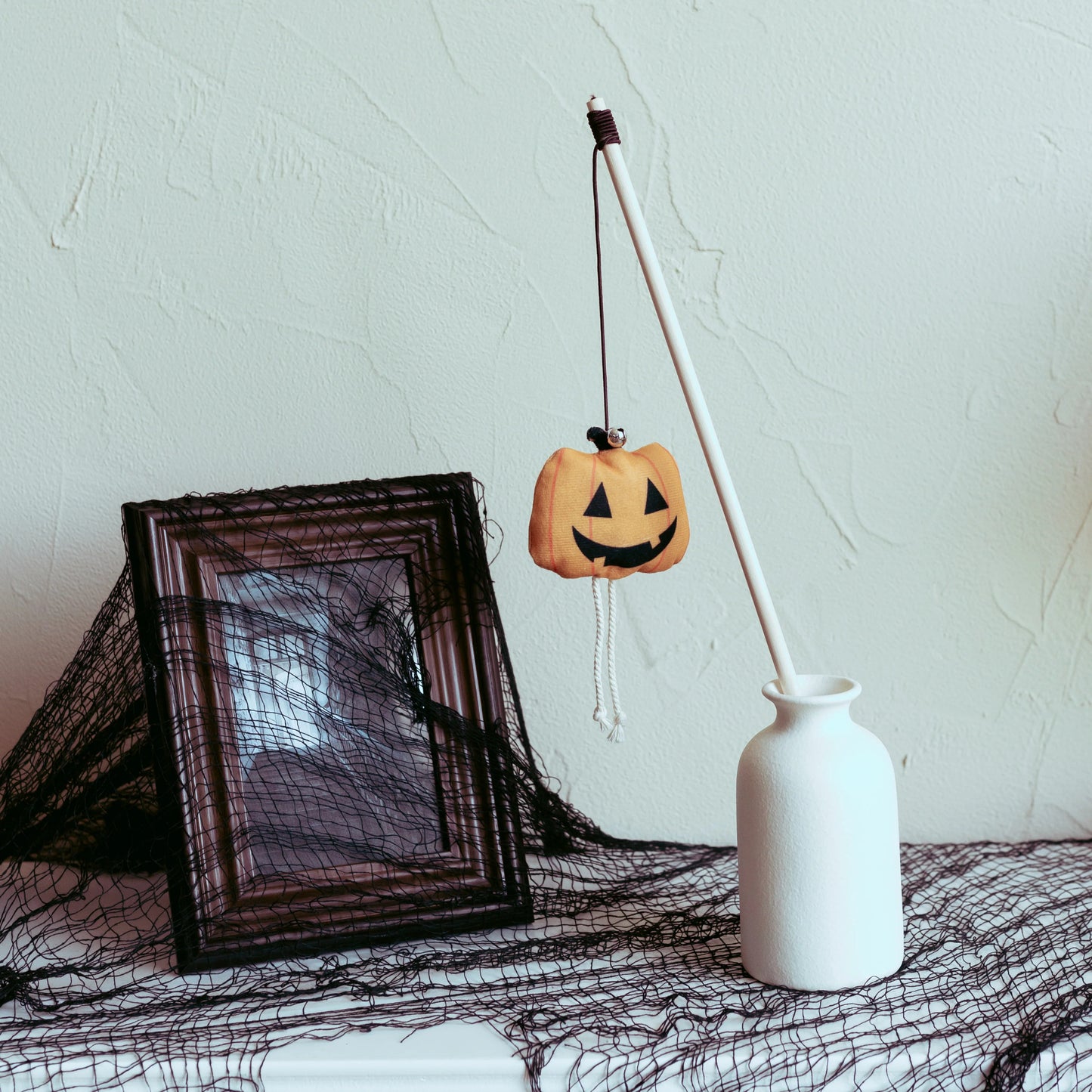 Halloween-themed cat teaser with a pumpkin and spooky skull design