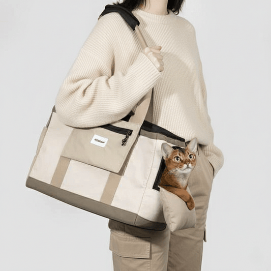 KtKitty Pet Carrier for Large Cats featuring a leg-out and lightweight design. A Caucasian model in a color-coordinated outfit carries the cat sling against a clean, minimalist background. This image highlights the secure leg-out openings, breathable fabric, and comfortable hands-free design for larger cats.